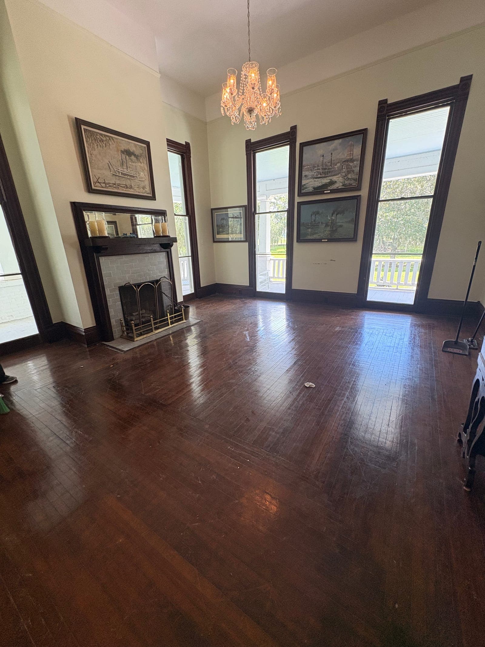 Empty parlor with a gleaming hardwood floor and a dust mop resting against the wall
